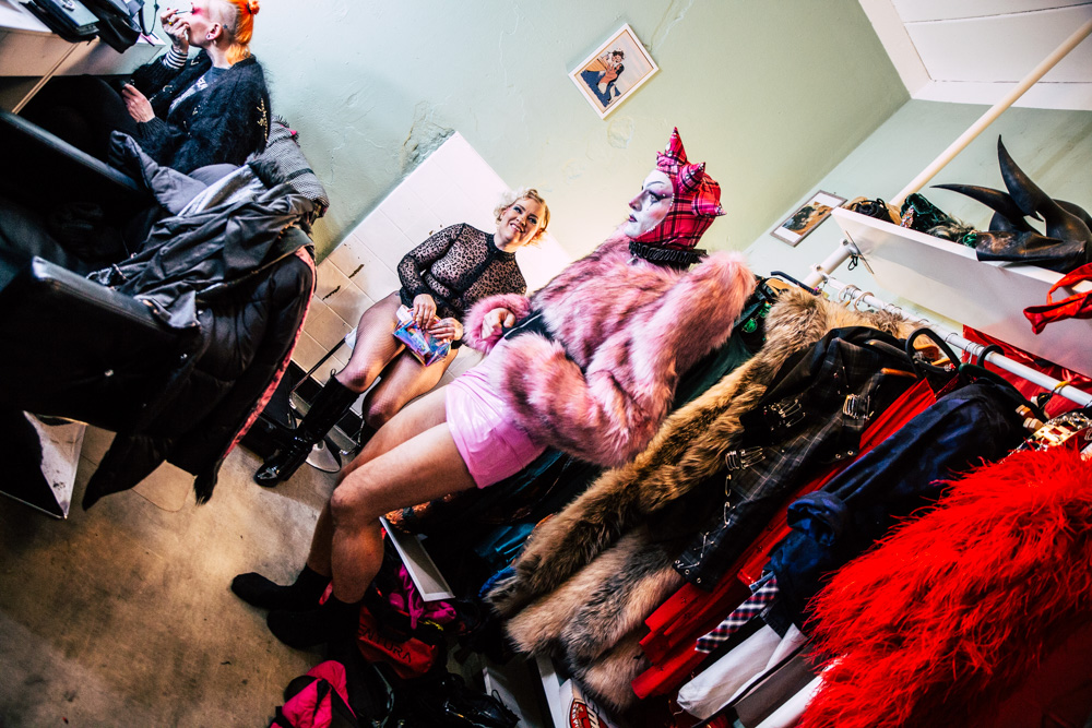 burlesque_041 Performer*in wird backstage beim Ankleiden unterstützt, andere Beteiligte bereiten sich im Hintergrund vor.