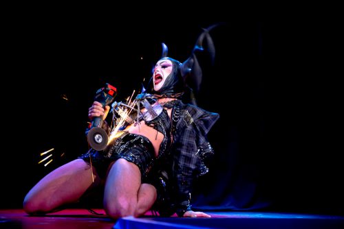 burlesque_05 Harpy Fatale kniet auf der Bühne und performt mit einer Schleifmaschine, Funken fliegen während der Show.