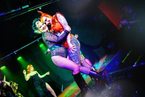 burlesque_20 Zwei Burlesque-Performerinnen stehen eng umschlungen auf der Bühne während einer gemeinsamen Performance.