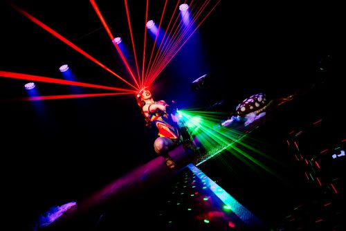 burlesque_34 Burlesque-Performerin kniet auf dem Laufsteg, rote Laserstrahlen fächern sich über den Bühnenraum.