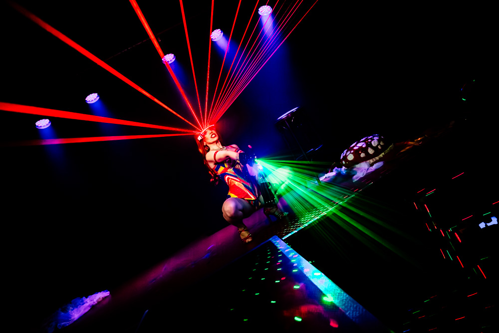 burlesque_34 Burlesque-Performerin kniet auf dem Laufsteg, rote Laserstrahlen fächern sich über den Bühnenraum.